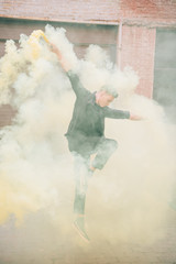 young male contemporary dancer jumping in smoke on urban street
