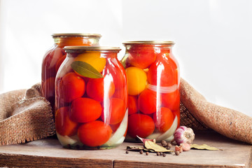 Glass jars with red pickled tomatoes, sealed with metal lid