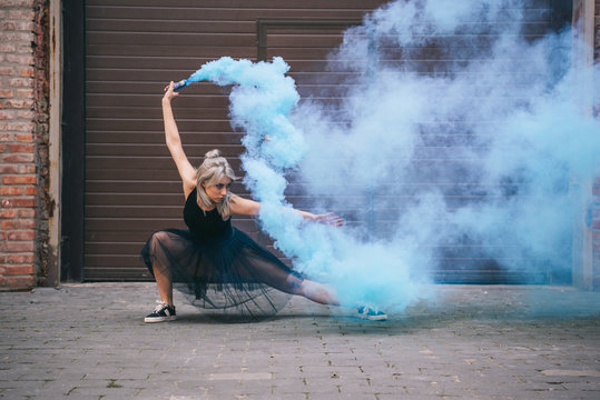 young contemporary dancer dancing in blue smoke on street