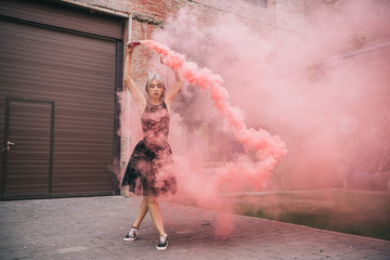 young woman dancing in pink smoke on urban street