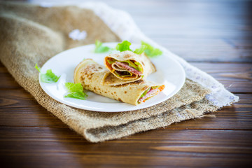 thin pancakes with salad leaves and bacon in a plate