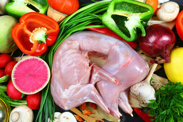 Raw rabbit meat with fresh vegetables background. The concept of dietary nutrition. Flat lay top view