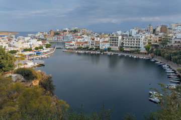 Fototapeta na wymiar View from the hill to the bay with boats and the city of Agios Nikolaos at the end of autumn day