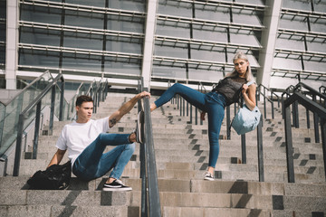 stylish sporty young couple with backpacks posing on stairs
