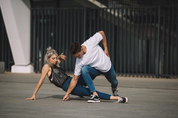 Fototapeta na wymiar young man and woman dancing on urban city street