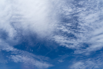 View of beautiful abstract splash soft white cloudscape with shades of bright blue sky background from flying plane window in the afternoon light