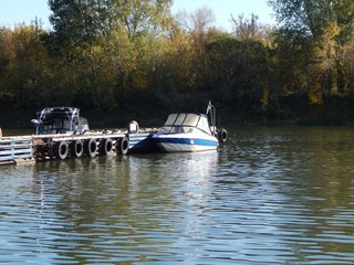Fototapeta premium Motorboat on the pier. Boat on the lake near the pontoons in the fall. A photo.