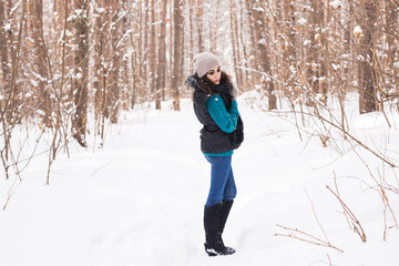 Fototapeta na wymiar Young pretty woman walking in the winter snowy park at sunny day