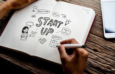 Man drawing start up in a notebook