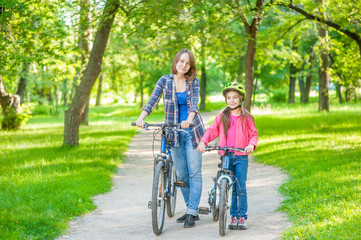 Mom and daughter are cycling in the park together