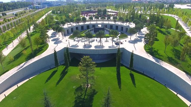 Aerial view: drone fly from Amphitheater boy with dad by hand go to cinema park. Aerial footage cityscape Kuban summer. Beautiful view park Krasnodar.