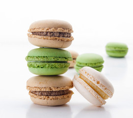 Macarons apilados de color crema y verdes sobre un fondo blanco