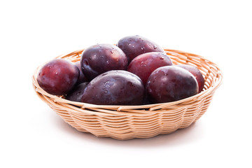 Yellow wooden basket with ripe plums isolated on a white background..