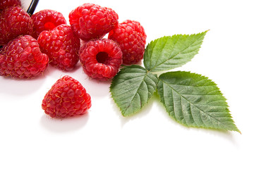 White cup with ripe raspberries and green leaf isolated on white background.