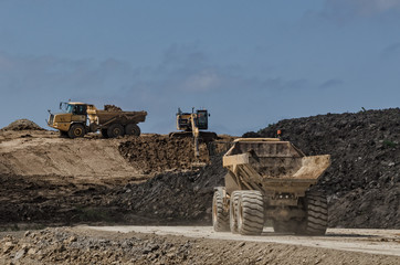 CONSTRUCTION MACHINERY - Tipper trucks and excavator on construction side © Wojciech Wrzesień
