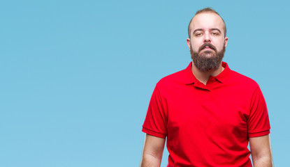 Young caucasian hipster man wearing red shirt over isolated background with serious expression on face. Simple and natural looking at the camera.