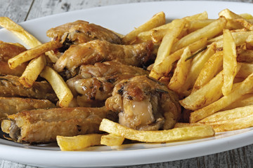 piatto ovale ali di pollo arrosto con patatine fritte sopra