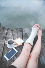 Leg pain in the legs to prevent inflammation..Coffee, bread, smartphone on wooden floor in the morning.Do not focus on objects.Warm tone.