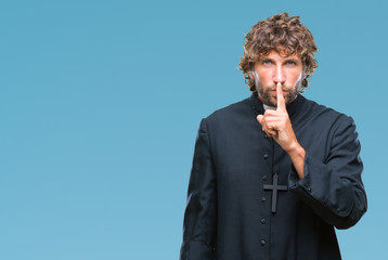 Handsome hispanic catholic priest man over isolated background asking to be quiet with finger on...