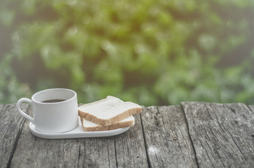White bread and glass placed on the table in the morning.On the breakfast table there was a glass of coffee and a plate of bread.Do not focus on objects.