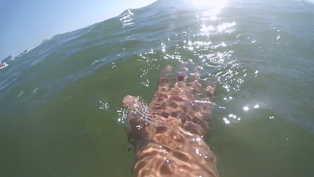 Slow motion POV. Scene point of view the hand glides slides on the surface of the water on a sunny day with natural sunny light rays close-up. Ocean sea summer concept. Top view