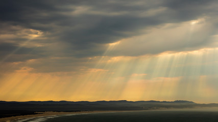 Sunrays shining through stormy clouds over the sea at Jeffreys Bay, South Africa