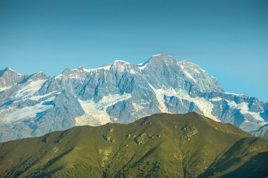 Distinct view of mountains with green nature and white mountains in the background in northern Italy