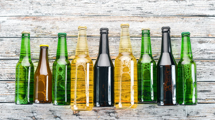 A large selection of beer bottles. On a white wooden table. Free space for text. Top view.
