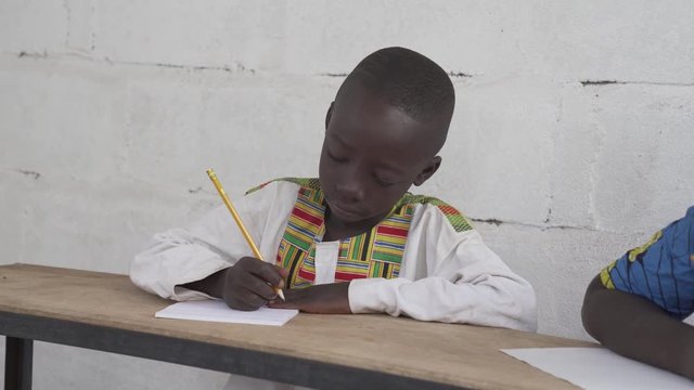 Black native African boy in a school in a village in rural Africa. 4K RAW clip, please modify and edit (color grade, stabilize, etc.) in postproduction.