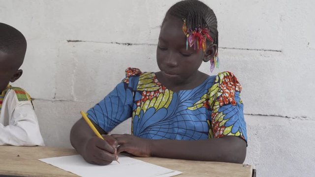 Beautiful footage of an African girl writing and learning at school. 4K RAW clip, please modify and edit (color grade, stabilize, etc.) in postproduction.
