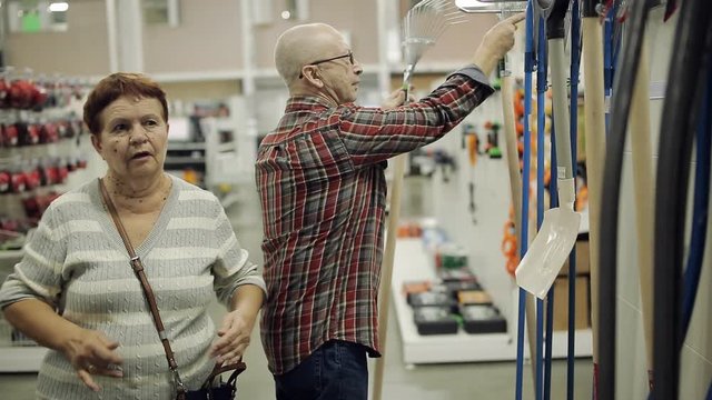 An elderly couple at a hardware supermarket choose rake