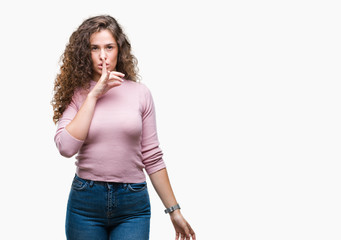 Beautiful brunette curly hair young girl wearing pink sweater over isolated background asking to be quiet with finger on lips. Silence and secret concept.