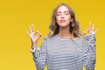 Beautiful young blonde woman wearing stripes sweater over isolated background relax and smiling with eyes closed doing meditation gesture with fingers. Yoga concept.