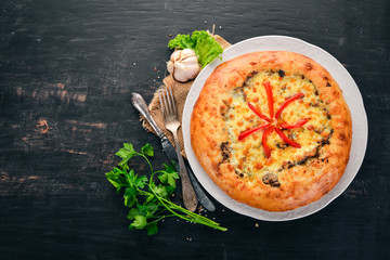Khachapuri with cheese, mushrooms and paprika. On the old wooden background. Free space for text. Top view.