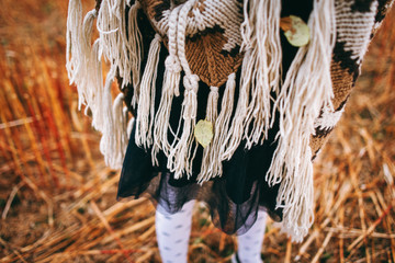 Atmospheric autumn background. Poncho on a girl in a field with several leaves. Girl in autumn mood
