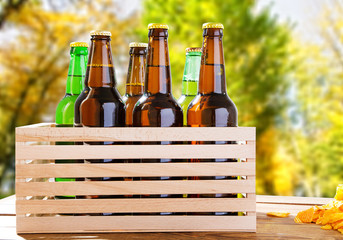 beer bottles on wooden table with blurred forrest on background, coloured bottle, food and drink...