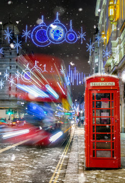 Einkaufsstraße in London mit Schnee, Telefonzelle, rotem Bus und Festbeleuchtung zu Weihnachten