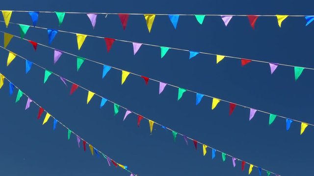 Multi colored flags on the blue sky.
Pennants moved for the wind, symbol of celebration and fun.