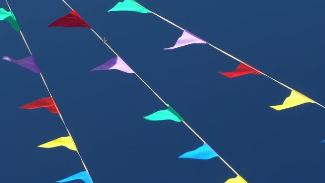 Multi colored flags on the blue sky.
Pennants moved for the wind, symbol of celebration and fun.