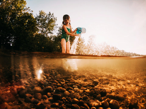 Girl Standing In A Lake Emptying A Bucket Of Water, Lake Superior, United States