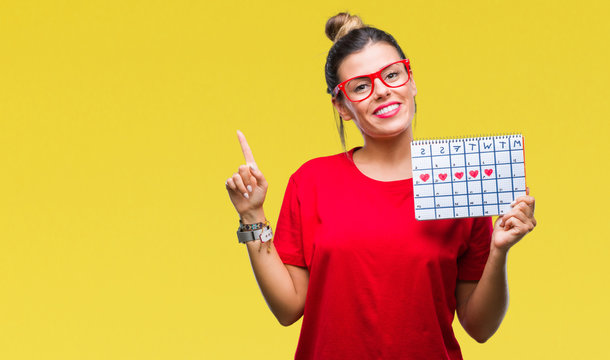 Young beautiful woman holding menstruation calendar over isolated background very happy pointing with hand and finger to the side