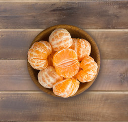 Top view. Fresh tangerines on a wooden background. Mandarins in a wooden bowl with copy space for text. Ripe and tasty tangerines. Clementines on a wooden table. Background tangerines.