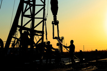 The oil workers are working in the sunset silhouettes