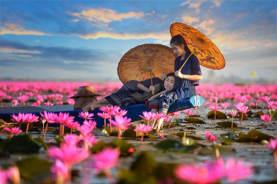 Two women sitting on a boat in a lotus flower lake, Thailand