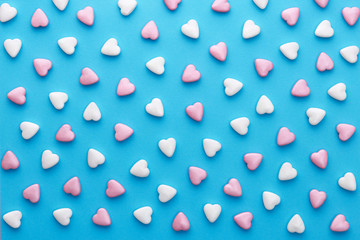 Heart shaped candies pattern on a blue background. Top view