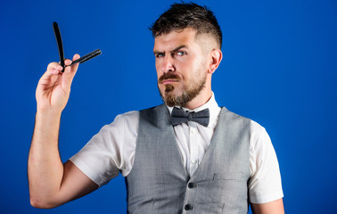 Man vest with bow tie hold straight razor blue background. Barber vintage art concept. Barber...