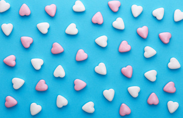 Heart shaped candies pattern on a blue background. Top view