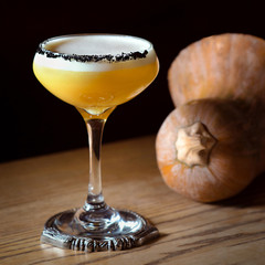 pumpkin alcohol cocktail in a glass and pumpkin on the table