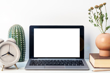 Hipster wooden desk with an open laptop mockup, concrete clock, ceramic decoration with a cactus, a book and a vase with dried flowers