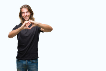 Obraz na płótnie Canvas Young handsome man with long hair over isolated background smiling in love showing heart symbol and shape with hands. Romantic concept.